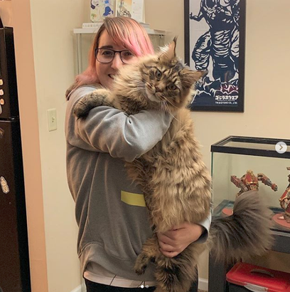A woman holding onto a large cat in her arms.